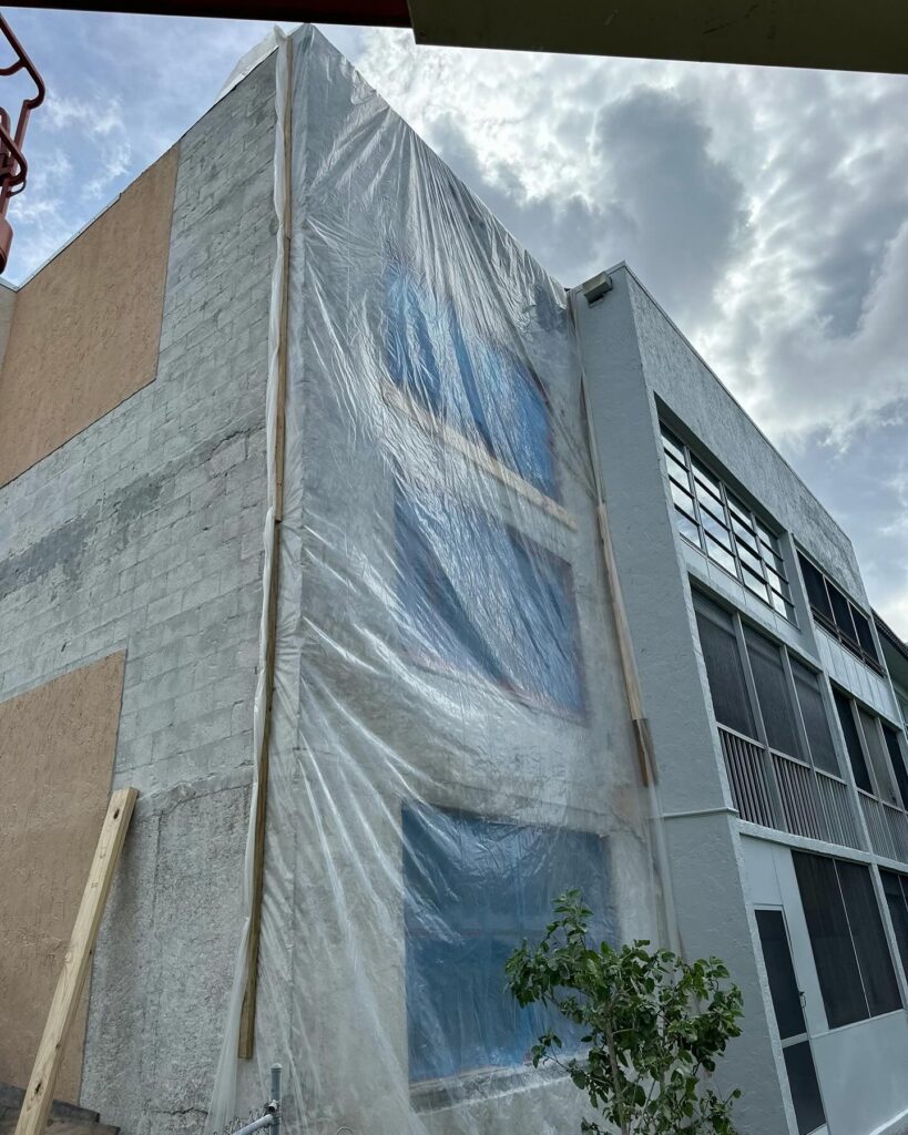 Repaired walls wrapped in specialized plastic film to control moisture loss and maximize concrete curing strength.